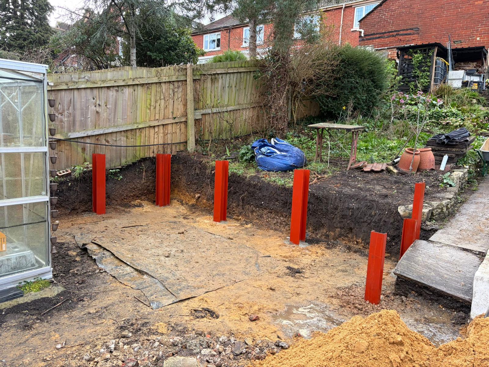 Steel posts set deep into concrete footings to anchor the retaining wall